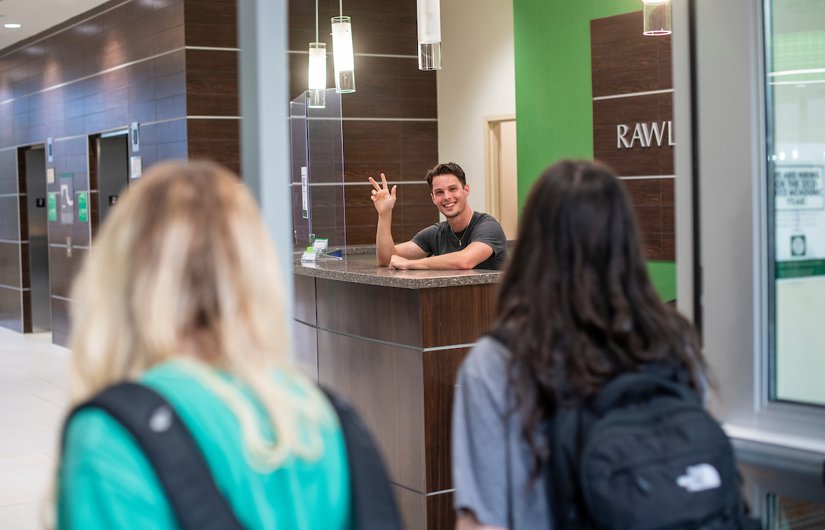 person welcoming students at desk 