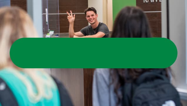 person welcoming students at desk 