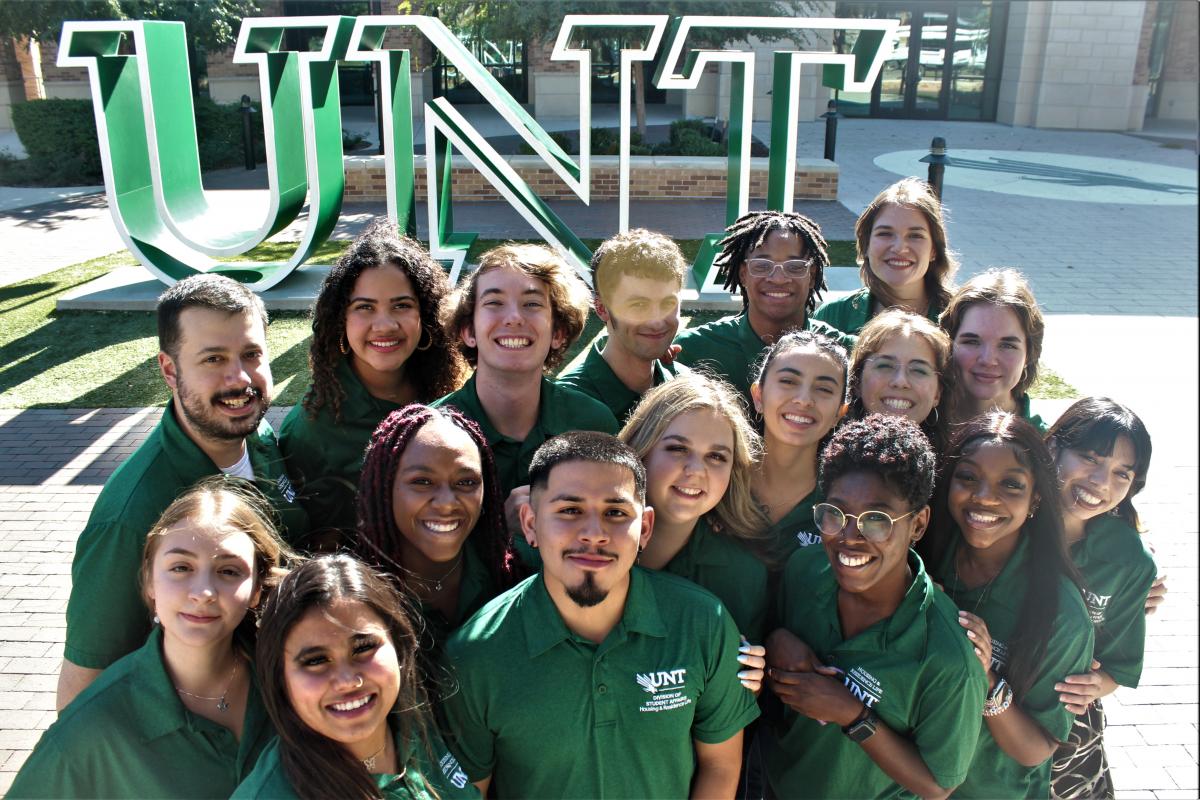 group photo of Housing Ambassador staff by UNT sign